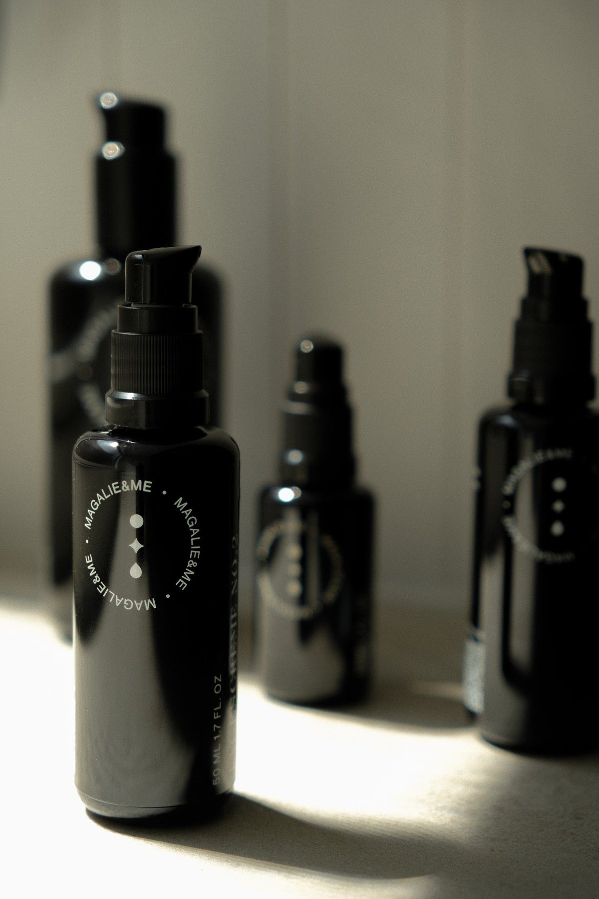 Dark violet glass skincare bottles in soft light