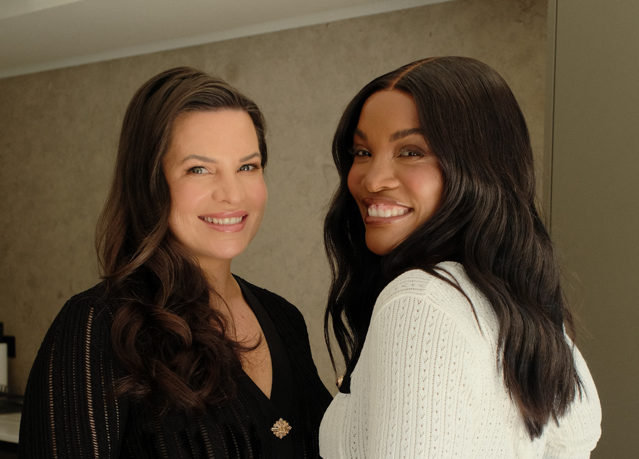 Two women founders of Magalie & Me standing close together, one in a black outfit and the other in a white outfit, against a neutral background.