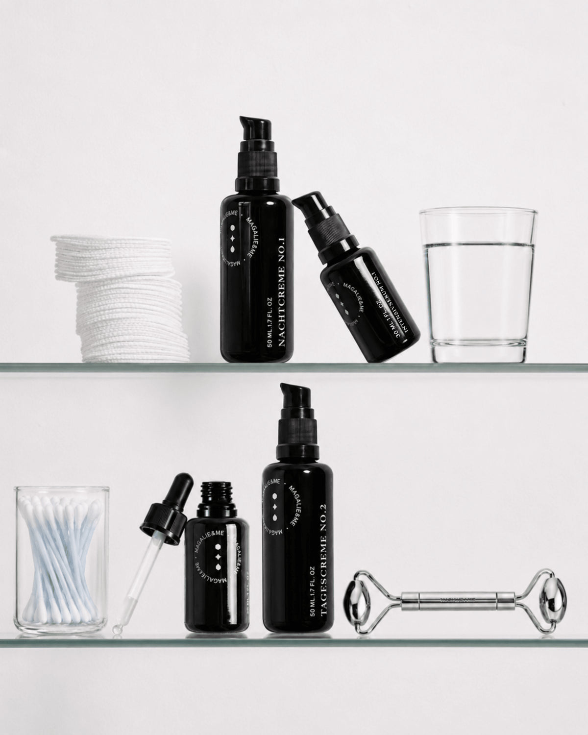 Magalie&ME skincare bottles on a glass bathroom shelf with a face roller and cotton buds