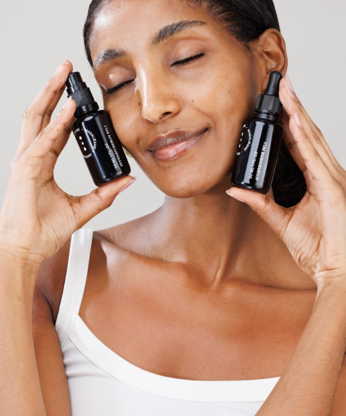 Woman with eyes closed holding two Magalie&ME bottles to her face