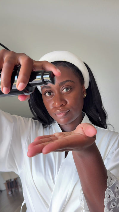 Woman in a white robe pumping Cleansing Oil No. 1 into her hand