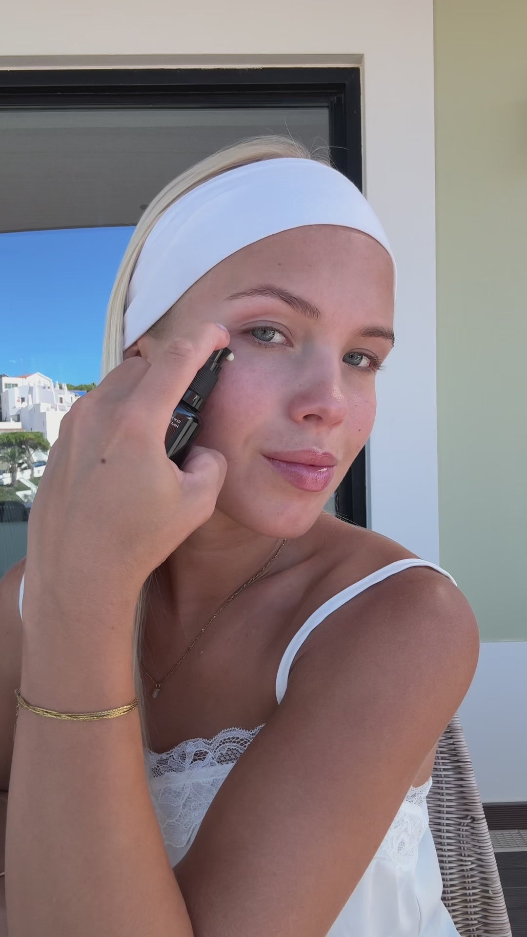 Woman in a headband applying Intensive Renewal Serum No. 1 in the sun