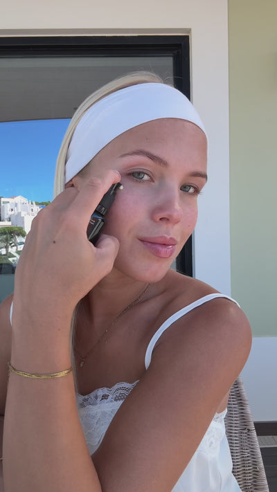 Woman in a headband applying Intensive Renewal Serum No. 1 in the sun
